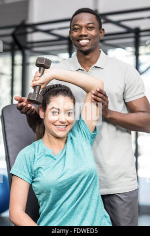 Sportliche Frau Heben von Gewichten von Trainer geholfen Stockfoto