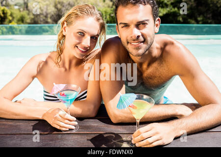 Glückliches Paar stützte sich auf den Beckenrand und halten cocktails Stockfoto