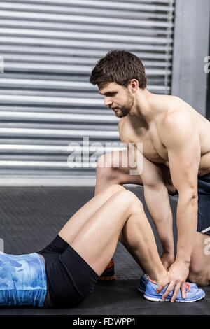 Männlichen Trainer Frau mit Sit-Ups zu unterstützen Stockfoto