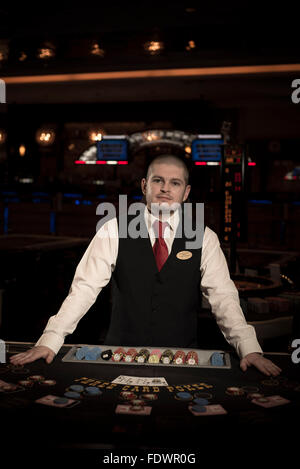 ein Croupier posiert für die Kamera in einem Casino bereit für Menschen zu beginnen, Glücksspiel mit Karten oder am Roulette-Tisch Stockfoto