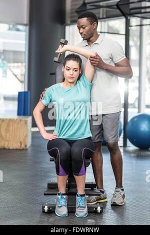 Sportliche Frau Heben von Gewichten von Trainer geholfen Stockfoto