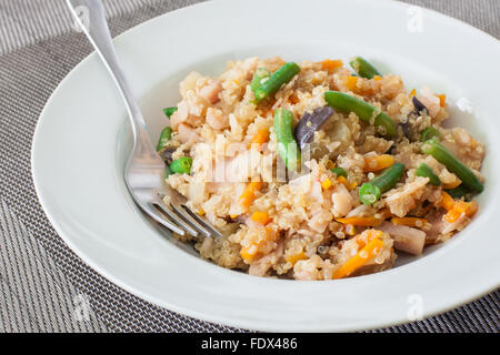 Quinoa mit Gemüse auf weißen Teller mit Gabel Stockfoto