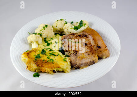 Gebratenes Schweinefleisch Shop und Kartoffelpüree mit Blumenkohl und Sauce Bearnaise mit Petersilie obenauf isoliert auf weiss. Stockfoto