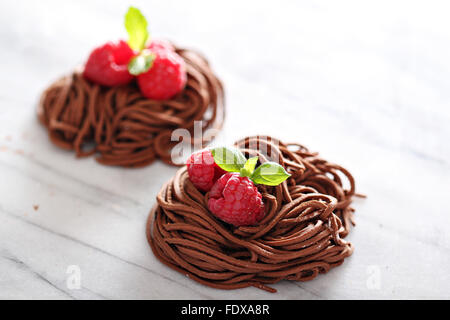 Rohe Schokolade Nudeln Nester mit Himbeeren auf Marmor Stockfoto