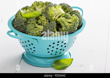 Frische Broccoli-Röschen in blau Sieb auf weiß Stockfoto