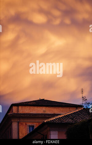 Dramatische orange Gewitterwolken über geflieste Dächer in Rom, Italien Stockfoto
