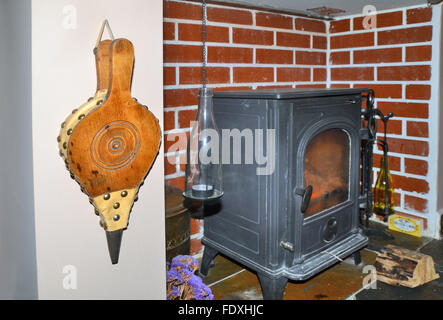 Holzfeuer Faltenbalg hängen in der Nähe ein indoor Holzofen befindet sich im umgebauten Kamin. Stockfoto