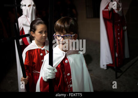 Ein Junge hält ein Kreuz und einen Umhang tragen, während einer Prozession der Karwoche in Trujillo, Extremadura, Spanien. Stockfoto