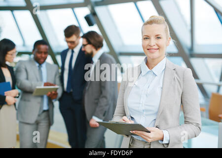 Junge Geschäftsfrau mit Zwischenablage Notizen im Arbeitsumfeld Stockfoto