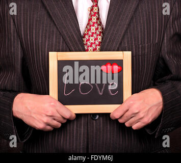 Geschäftsmann hält einem ein Schild mit der Aufschrift Liebe und Herzen als Symbol für Valentinstag Stockfoto