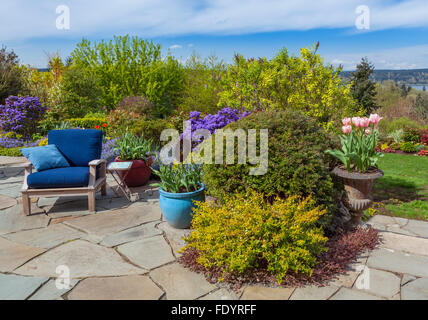 Maury-Vashon Island, WA: Steinplatten Terrasse mit blauen Stuhl und bunte Tulpen mit mehrjährigen Gärten Stockfoto