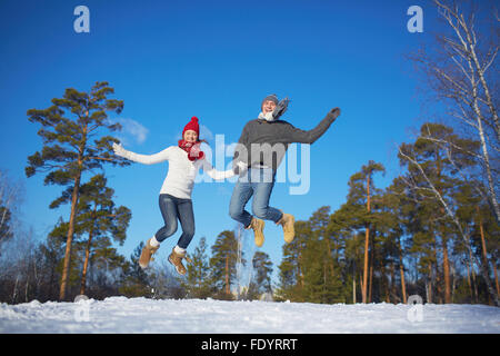 Junge Valentines in gestrickte Kleidung springen in Winter Park oder Wald Stockfoto
