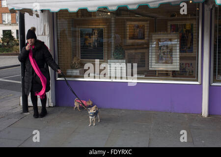 Ein Hundebesitzer raucht eine Zigarette, während ein Qalk für ihre geliebten Haustiere in Waterloo, Südlondon. Stockfoto