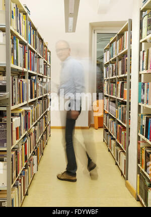Mann stehend und Buch in der Bibliothek in Pula. Stockfoto