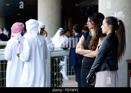 Dubai, Vereinigte Arabische Emirate, Männer in Tracht und elegant gekleidete Frauen mit Hut bei den Rennen Stockfoto
