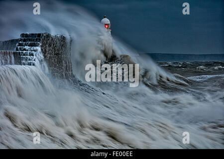 Große Wellen kollidieren in die kaimauer als Sturm hits Leuchtturm, Porthcawl. In Bridgend, Südwales, Vereinigtes Königreich Stockfoto