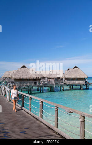 Frau zu Fuß auf der Mole des Wasserbungalows des Sofitel Hotel, Moorea, Gesellschaftsinseln, Französisch-Polynesien Stockfoto