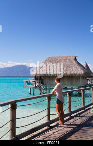 Frau an einem Anlegesteg der Wasserbungalows von Sofitel Hotel, Moorea, Gesellschaftsinseln, Französisch-Polynesien Stockfoto