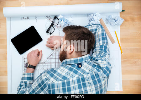 Draufsicht der erschöpften bärtiger junger Architekt schlafen am Arbeitsplatz Stockfoto