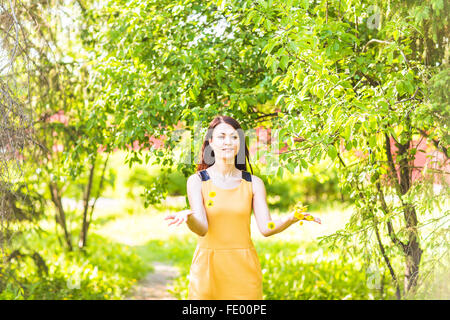 asiatische Frau werfen Blütenblätter im Frühlingsgarten Stockfoto