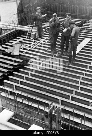 Das Motiv aus der nationalsozialistischen Propaganda zeigt die Bauarbeiten an einer Festung am Atlantikwall, herausgegeben im Dezember 1942. Die nationalsozialistische Propaganda auf der Rückseite des Bildes lautet: 'Der Atlantikwall. Besprechungen zwischen Festungspionier und OT-Mann [OT = Organisation Todt] auf einem Bau. Der Festungspionier plant und überwachen, die OT [= Organisation Todt] führt den Bau aus." Fotoarchiv für Zeitgeschichte/Archiv - KEINE BILDFUNKVERWENDUNG - Stockfoto