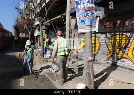 Thessaloniki, Griechenland. 3. Februar 2016. Arbeiter reparieren einen Gehsteig vor dem Plakat kündigt einen Generalstreik und einer Kundgebung. Griechischen öffentlichen und privaten Sektor Gewerkschaften forderten eine landesweite allgemeine am Donnerstag Againts Regierung geplante Rentenreform zu protestieren, die 3. internationale Rettungsaktion des Landes gehören. Öffentlichen Verkehrsmitteln ist zu stark gestört werden ausgenommen und Taxifahrer werden voraussichtlich an der Maßnahme teilnehmen. Bildnachweis: Orhan Zolak/Alamy Live-Nachrichten Stockfoto