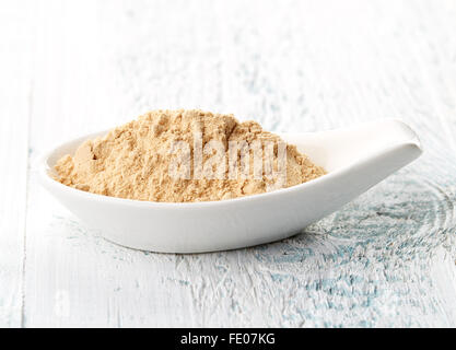 Maca Pulver in weißem Porzellanlöffel auf weißer Holztisch Stockfoto