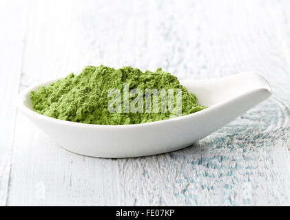 Junge Gerste oder Weizen Grass in weißem Porzellanlöffel auf weißer Holztisch Stockfoto