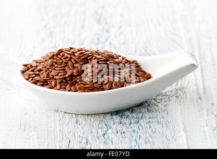 Leinsamen in weißem Porzellanlöffel auf weißer Holztisch Stockfoto