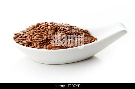 Leinsamen in weißem Porzellanlöffel auf weißem Hintergrund Stockfoto