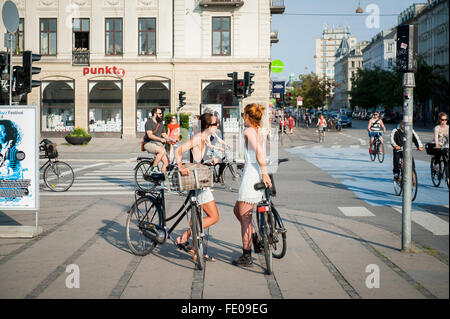 Junge Dänen, die auf dem Dronning Louises Bro im sonnigen Kopenhagen, Dänemark, mit dem Fahrrad durch die Stadt fahren Stockfoto