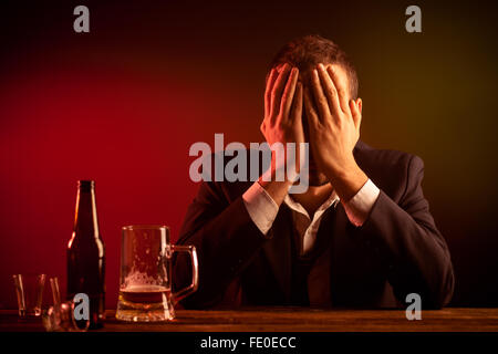 Betrunken Geschäftsmann in einer Kneipe versteckt sein Gesicht mit ihren Händen Stockfoto