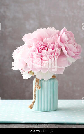 Rosa Pfingstrose Blumen in blauer Keramikvase. Grauer Hintergrund, Raum zu kopieren. Stockfoto