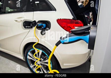 Ein Elektroauto wird an eine Ladestation angeschlossen und geladen wird. Stockfoto