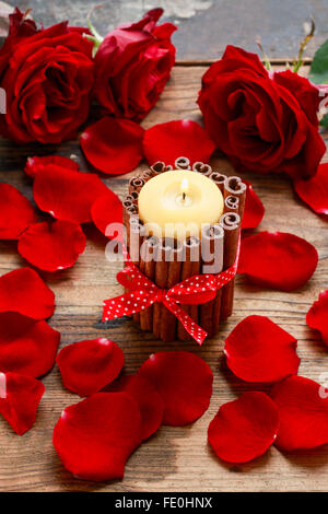 Kerze mit Zimtstangen unter Rosenblättern dekoriert. Romantische Dekoration. Stockfoto