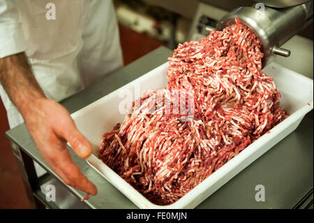 Nicht identifizierbare Metzger holding Tablett voller Hackfleisch roh rot verlassen Maschine in Essen-Aufbereitungsanlage Stockfoto