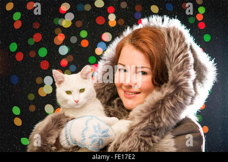 Ingwer-Mädchen im Pelzmantel tragen Handschuhe mit Katze Stockfoto