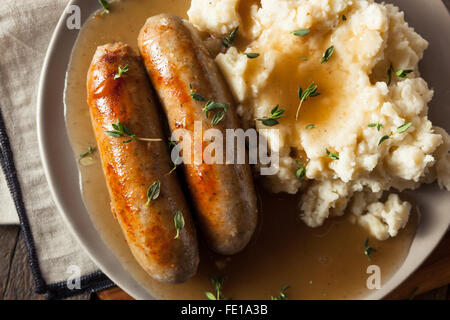 Hausgemachte Bangers and Mash mit Kräutern und Soße Stockfoto