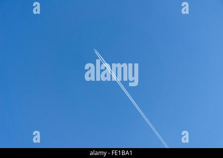 Verkehrsflugzeug und Jet Trail vor blauem Himmel Stockfoto