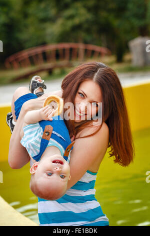 Mutter mit ihrem Baby zu spielen. Tochter hält einen Bagel. Picknick. Das Glück der Mutterschaft. Glückliche Kindheit. Stockfoto