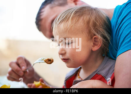 Junger Vater sein Kind Sohn Fütterung kleiner Junge am Tisch Stockfoto