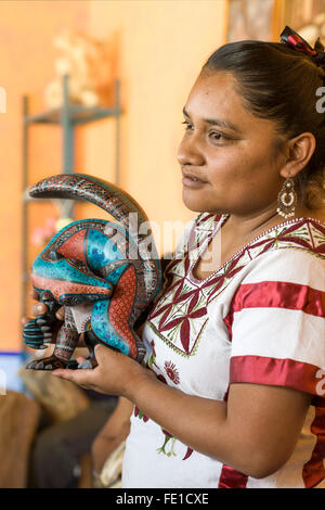 Zapotec Frau anzeigen fein gemalten Holz Handwerk schnitzen in der Werkstatt von Jacobo und Maria Angeles, San Martin Tilcajete, Oaxaca, Mexiko Stockfoto