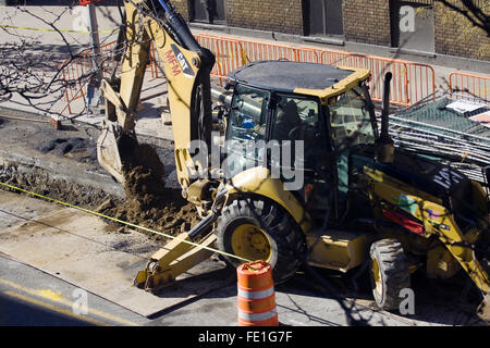 Bauarbeiter, Betrieb eine gelbe gemacht Baggerlader Caterpillar Corporation, die eine Stadt Graben Straße Stockfoto