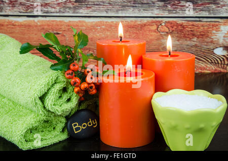 brennende orange Kerzen, Mineralsalz, orange Beeren, Lava-Stein und Handtuch-Still-Leben Stockfoto