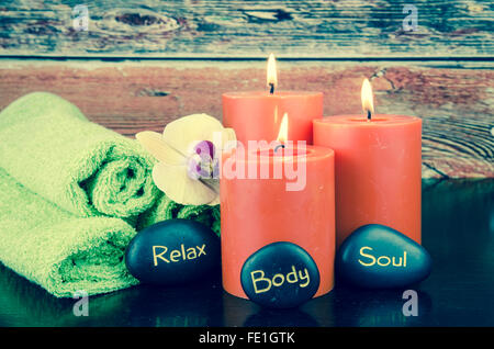 brennende orange Kerzen, orange Beeren, Lava-Stein und Handtuch-Still-Leben Stockfoto