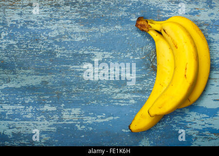 Reife Bananen auf alten blau lackierten Holztisch Stockfoto