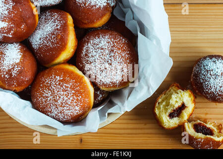 Hausgemachte Krapfen gefüllt mit rose Marmelade auf Holztisch. Rustikaler Stil Stockfoto