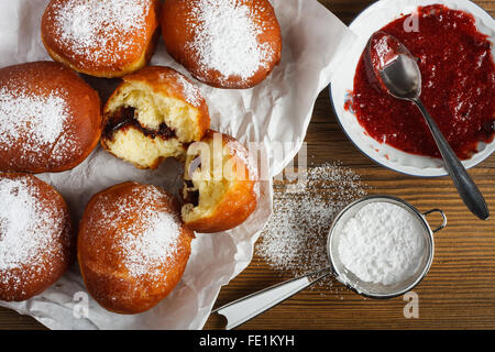 Hausgemachte Krapfen gefüllt mit rose Marmelade auf Holztisch. Stockfoto