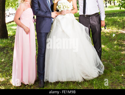 Glückliche Braut und Bräutigam mit Gästen im Garten stehen Stockfoto