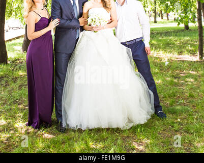 Glückliche Braut und Bräutigam mit Gästen im Garten stehen Stockfoto
